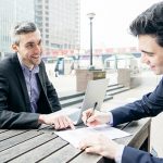 Business Meeting Outdoors, Businessmen Discussing A Contract Business Meeting outdoors, businessmen discussing a contract.